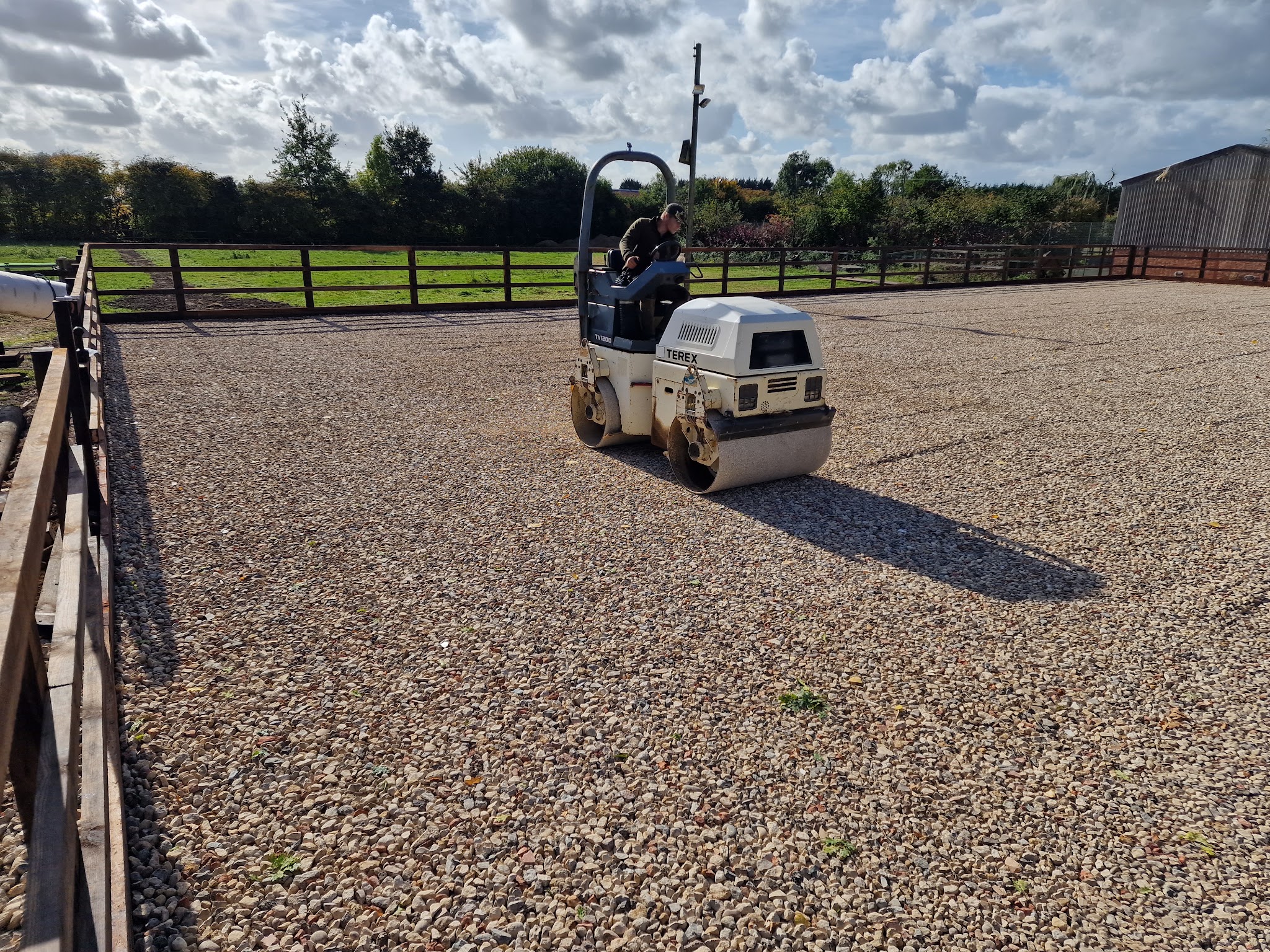 Roller compacting the stone base of an arena