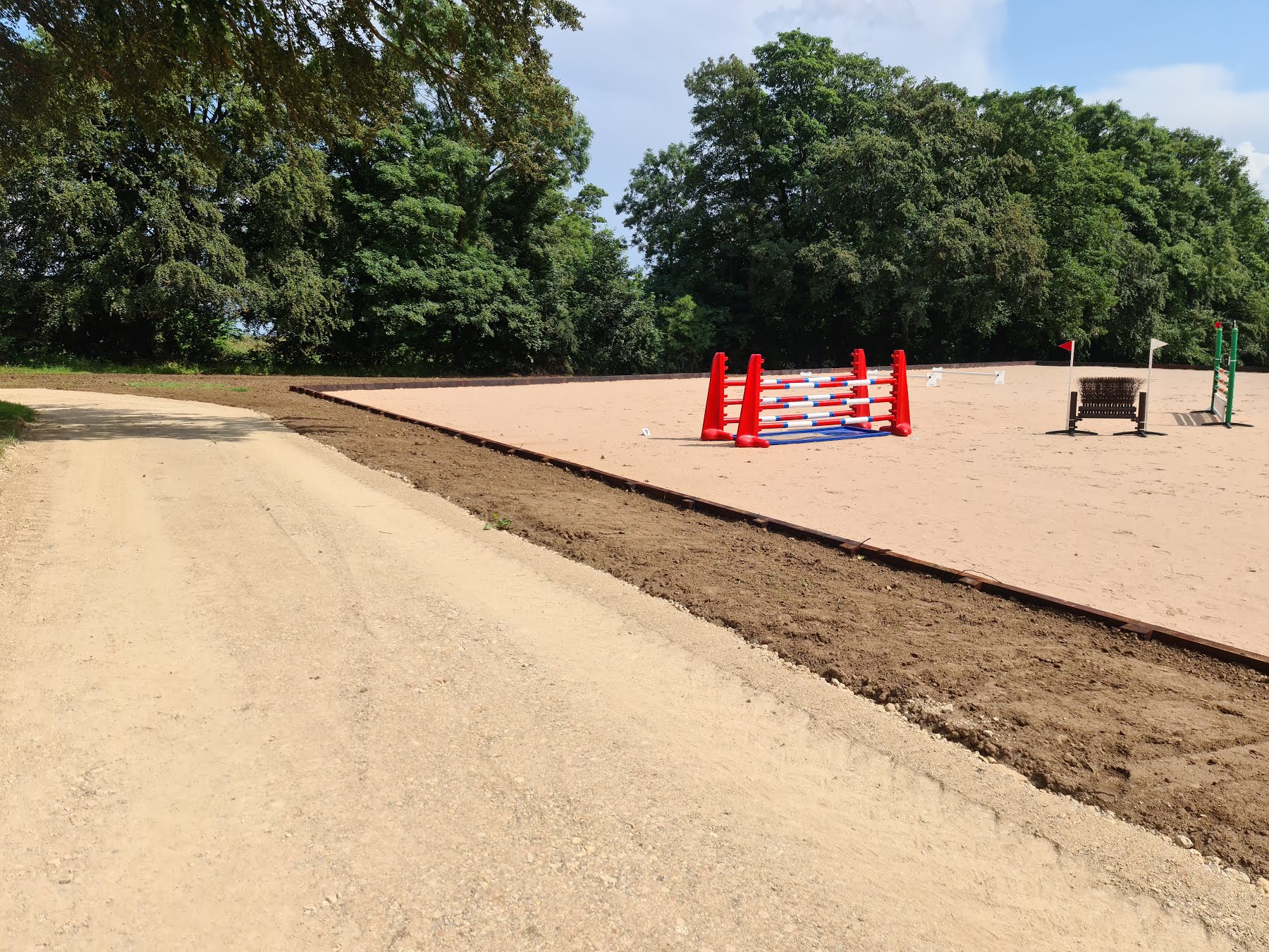 Sand arena with show jumps beside a new gravel track