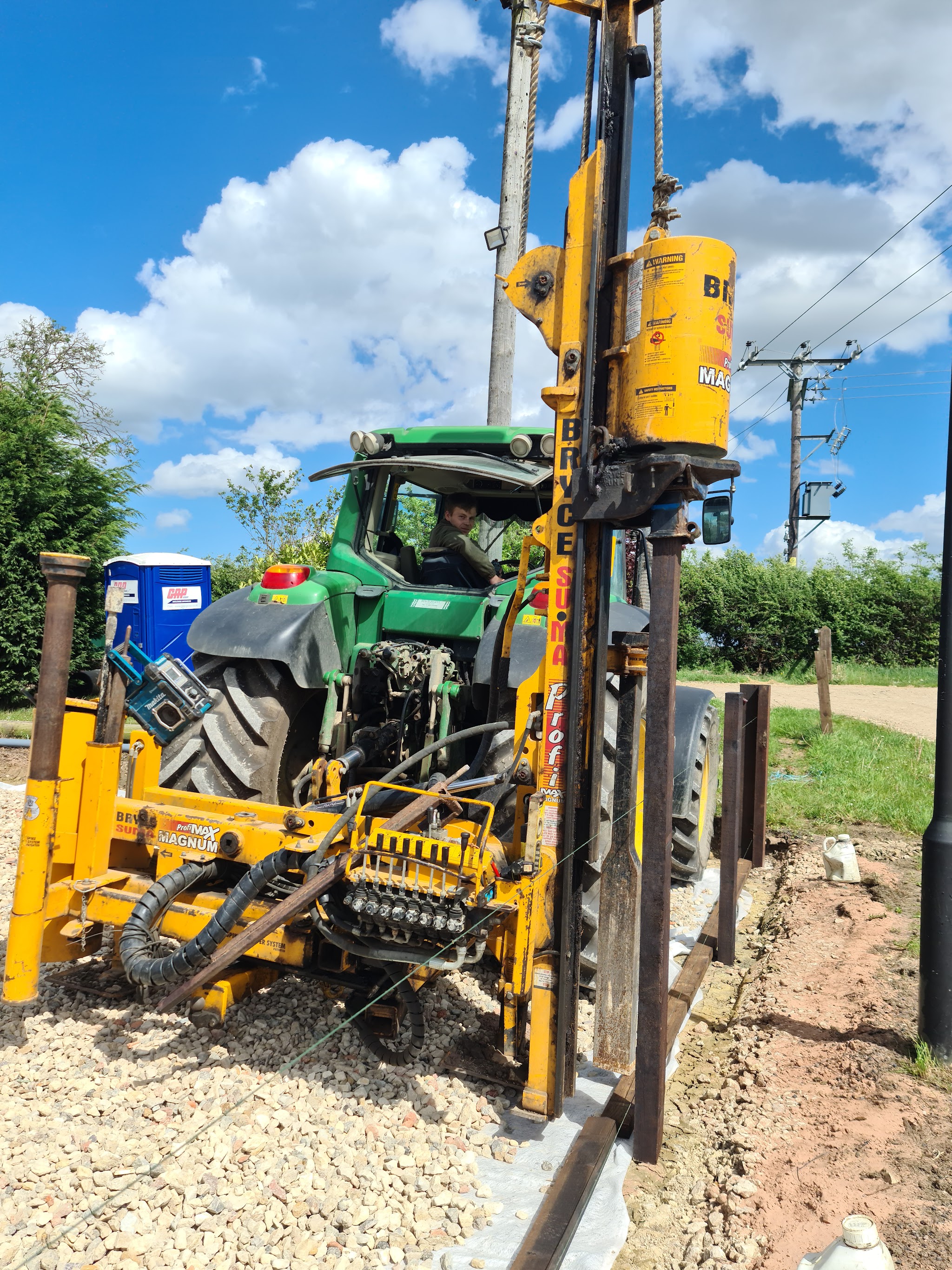 Tractor mounted post driver setting fence posts