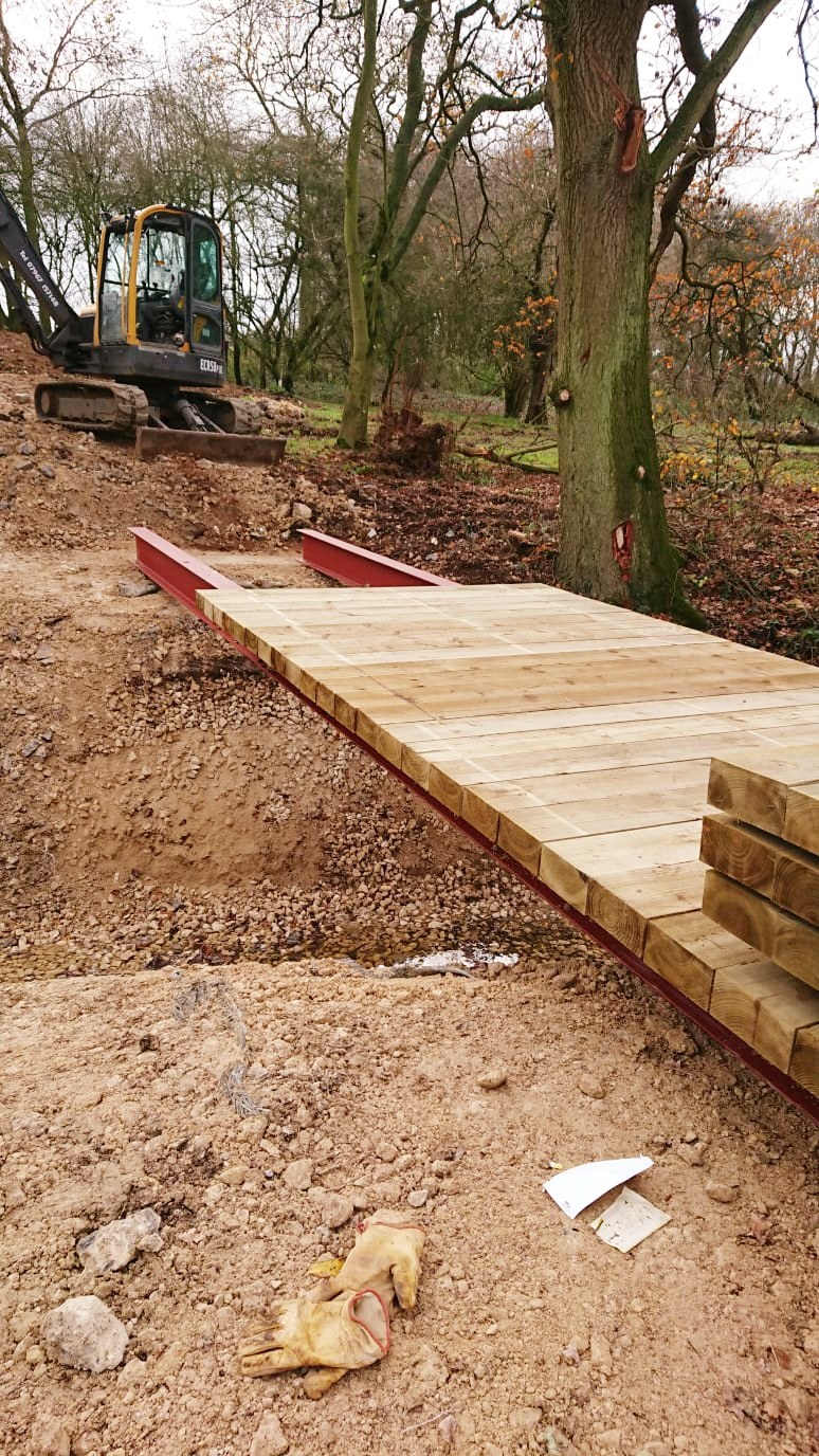 Timber footbridge and cleared path through woodland