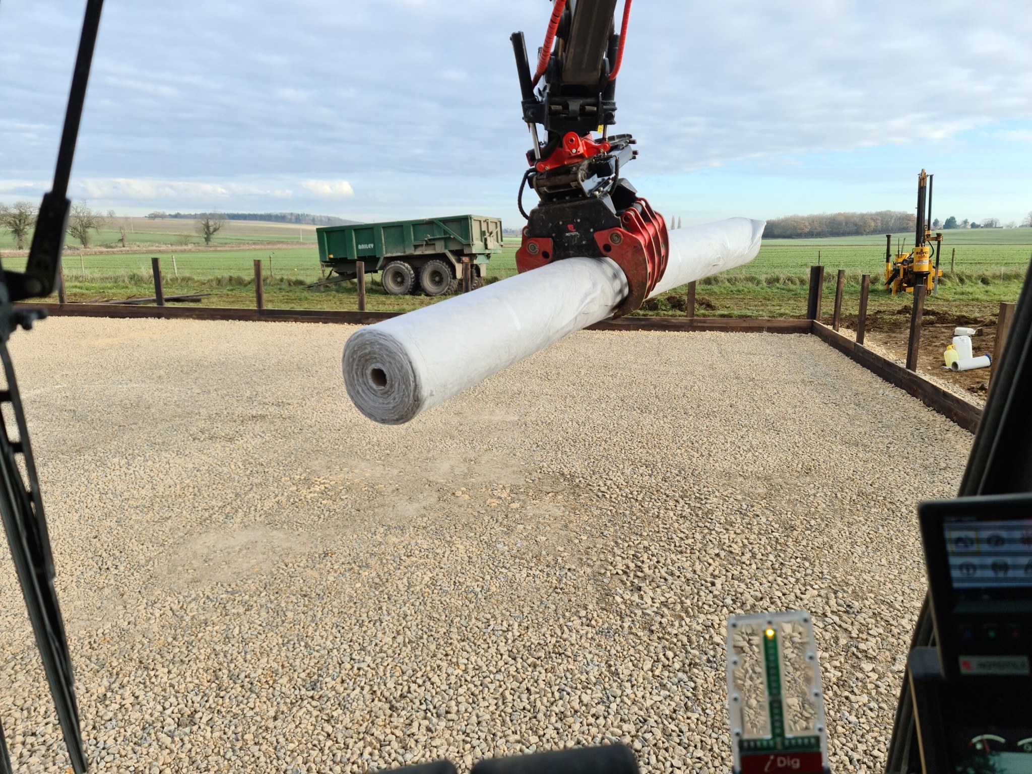 View from the excavator cab over a roll of geotextile