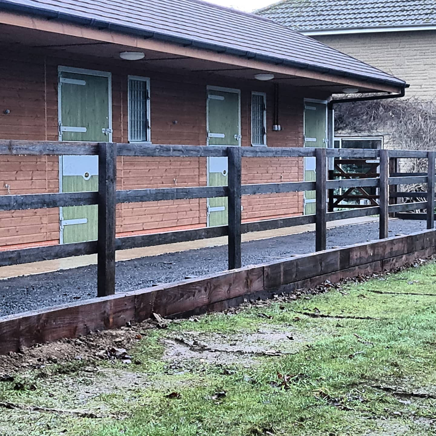 Post and rail fencing in front of new stables