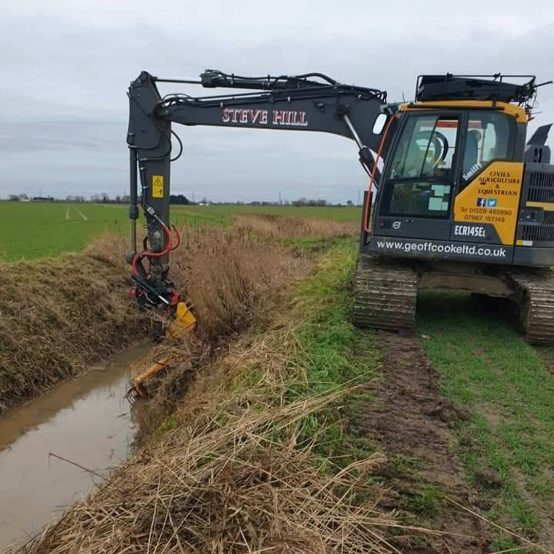 Excavator with Steve Hill on the boom cleaning out a field ditch