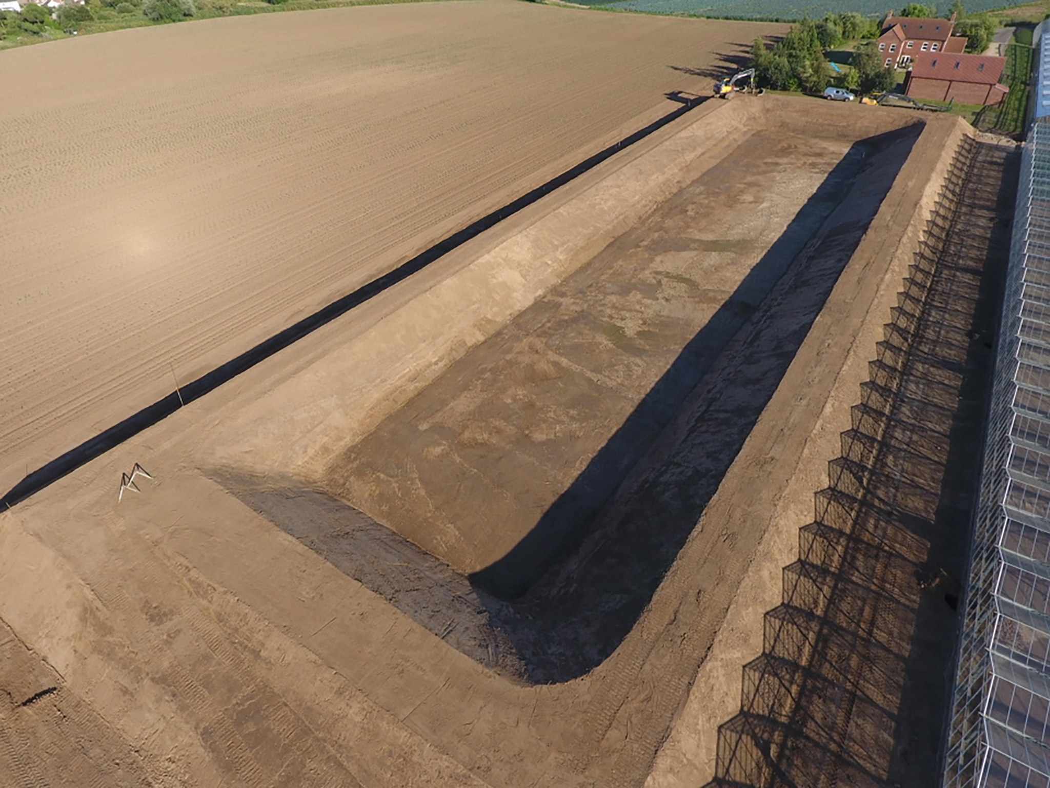 Aerial view of a new lined reservoir beside glasshouses