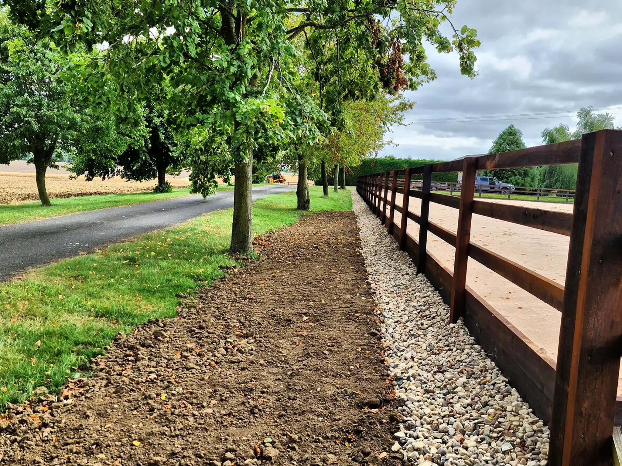 New fenced track beside a tree lined drive